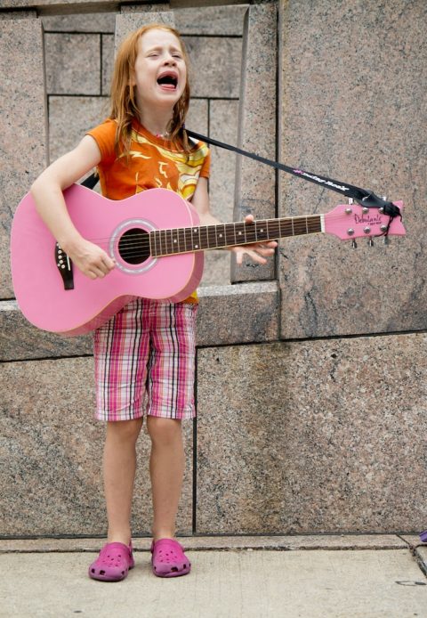 girl playing guitar near wall